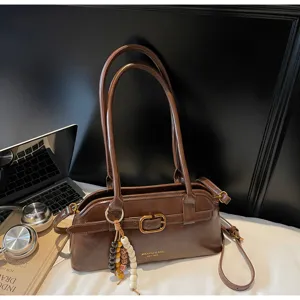 Retro brown leather shoulder bag detail showing vintage metal buckle and decorative beaded charm.