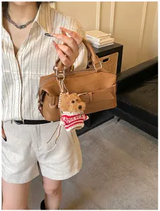 Detailed shot of trendy brown boston handbag featuring a cute plush dog charm pendant and modern style.