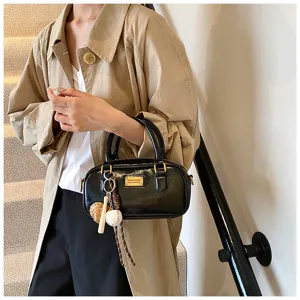 Stylish black patent leather Boston handbag for women, featuring cute sports charms and handle.
