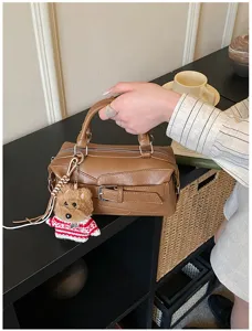 Close-up detail of stylish brown leather Boston handbag with cute puppy pendant charm.