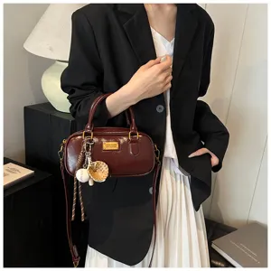 Detailed view of the dark red patent leather Boston handbag featuring chic baseball charms.