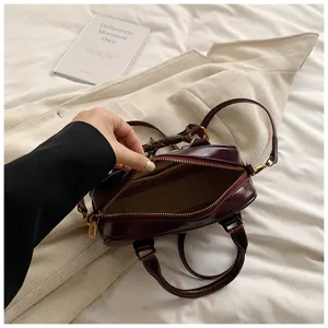 Burgundy leather boston bag detail showing interior compartment and metal zipper hardware.