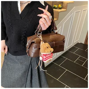 Detail view of the brown retro boston handbag, showcasing the stylish furry dog keychain pendant.
