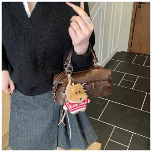 Detail view of a chic brown leather bowling bag with a cute plush puppy keychain attached.