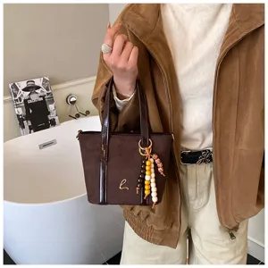 Retro brown faux suede tote bag for women, stylish bucket handbag with beaded pendant detail.