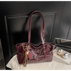 Vista dettagliata della borsa a mano bordeaux vintage con doppi manici e ciondoli chic.