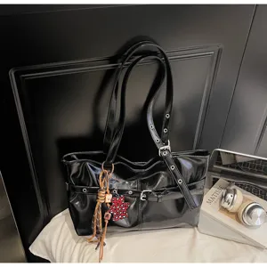 Vista dettagliata della borsa a spalla nera lucida con occhielli metallici e ciondolo.