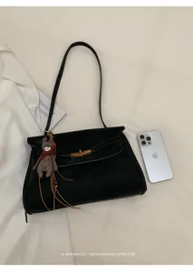 Schwarze Schultertasche Detail mit Metallschloss, süßem Bärenanhänger und feinem Riemen.