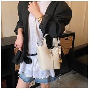 Detailansicht der eleganten Leder-Eimer Tasche mit Blumenanhänger und Tragegriffen.