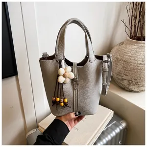 Graue Leder Eimer Tasche für Damen, stilvolle Handtasche mit Blumenanhänger, vielseitiges Design.