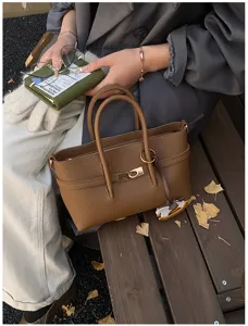 Detail view of the stylish brown textured tote bag showing premium metal lock closure and charm.