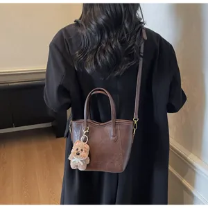 Retro bucket bag with plush dog charm, detailed view of texture, stylish shoulder handbag.