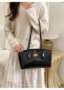Detalle de bolso de hombro en charol negro, elegante bolso de axila con doble correa fina.