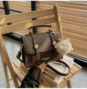 Vintage brown shoulder bag for women, classic crossbody messenger bag with cute plush charm.