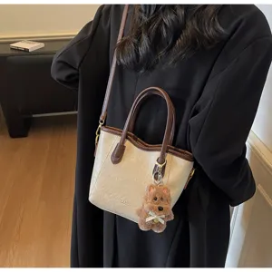 Retro two-tone bucket bag with cute bear charm, elegant crossbody shoulder bag for autumn.