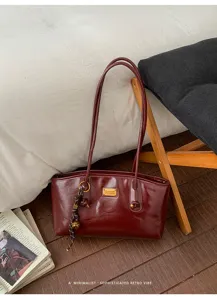 Bolso de hombro vintage de charol rojo angora con placa metálica elegante y detalle de colgante.