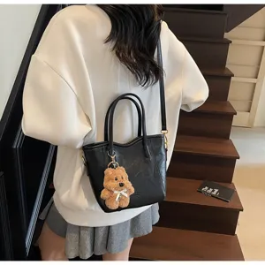 Detail view of retro black PU leather bucket handbag with cute fluffy bear keychain charm.