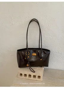 Primer plano del detalle del bolso de hombro rojo vintage con placa de metal y lindo dije.
