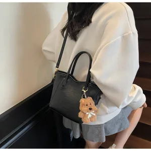 Black vintage tote bucket bag with cute bear plush pendant, stylish cross-body shoulder bag.