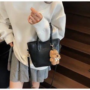 Black PU leather bucket bag with cute fluffy bear charm, retro trendy crossbody shoulder bag for women.