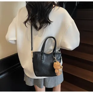 Classic black faux leather bucket bag with cute bear keychain for women crossbody everyday style.