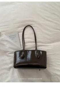 Bolso de hombro vintage de cuero marrón oscuro con correas dobles y nudos retro elegantes.