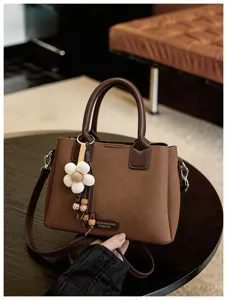 Vintage brown women's shoulder bag with floral charm and top handle, stylish bucket bag.
