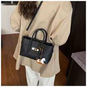 Black leather handbag detail showing metal turn-lock closure and cute rocking horse charm.