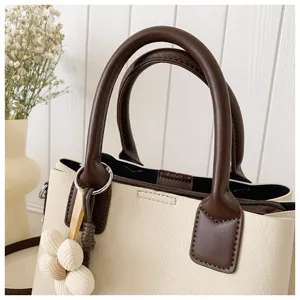 Close-up view of stylish two-tone handbag with flower charm, premium texture and details.
