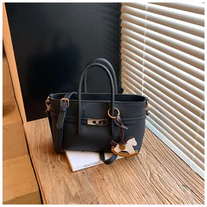 Black leather tote bag with top handle and crossbody strap, featuring cute horse charm detail.