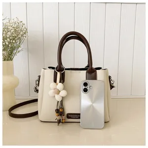 Chic retro contrast color bucket bag detail with floral pendant and adjustable strap.