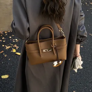 Brown leather shoulder bag tote women commuter crossbody bag with metal lock and charm.