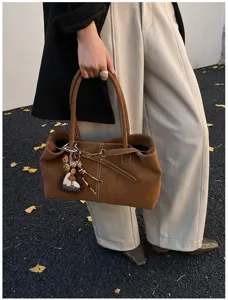 Brown suede tote bag detail view, stylish commuter shoulder bag with cute charms and double handles.