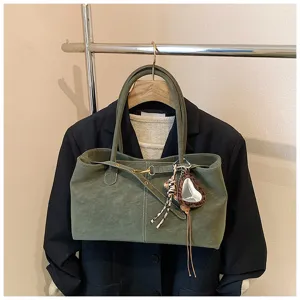 Green suede tote bag detail view, showing soft texture, metal hardware and chic heart mirror charm.