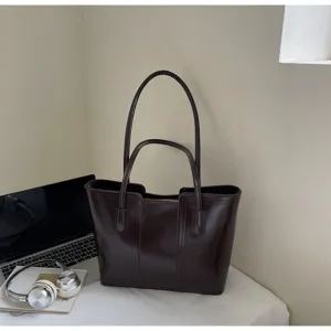 Nahaufnahme einer dunkelbraunen Tasche mit doppelten Griffen auf dem Schreibtisch mit Dekoration.