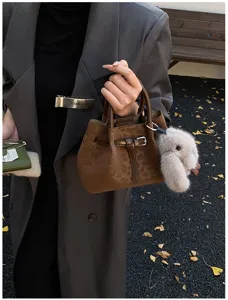Detail shot of brown leopard pattern bucket bag with fluffy bunny charm for women fashion.