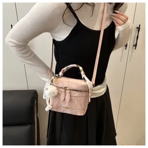 Vista detallada del elegante bolso cubo retro rosa con pañuelo de seda y colgante de peluche.