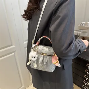 Elegante bolso de mano gris texturizado con bufanda y colgante esponjoso para uso diario.
