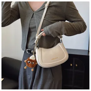 Vue détaillée d'un sac à bandoulière blanc élégant avec pendentif en peluche.