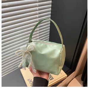 Vue détaillée du sac cosmétique vert frais avec pendentif nœud en perles, portable.