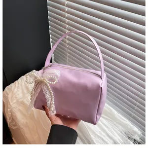 Vue détaillée de trousse de maquillage violette avec élégant nœud en dentelle de perles et poignée.