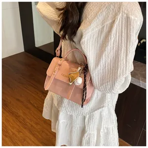Detalle de bolso bandolera rosa brillante, diseño retro elegante con colgante de béisbol.