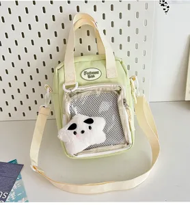 Detalle de bolso cruzado de lona estilo japonés con bolsillo de malla y colgante de estrella.