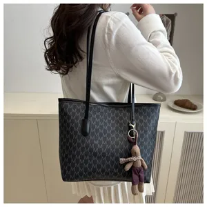 Detail view of large capacity black M monogram tote bag with a cute brown plush bunny charm.
