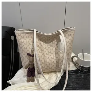 Stylish beige monogram tote bag with a cute rabbit plush pendant for daily casual work commute.