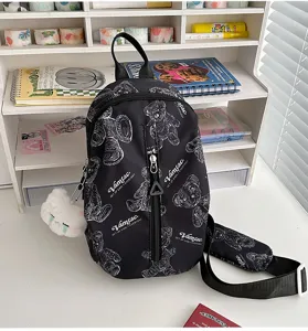 Schwarze bedruckte Umhängetasche für Damen, modischer Brustrucksack mit süßem Plüsch Anhänger.