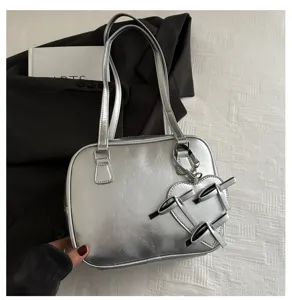 Bolso de hombro acolchado metálico plateado con colgante de lazo, accesorio elegante.