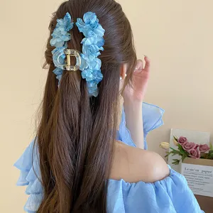 Blue floral hair claw clip detail showing elegant fabric petals and clear transparent acrylic base.