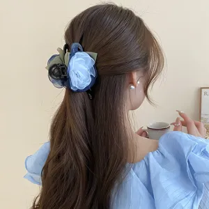 Detail view of a blue mesh flower hair claw, elegant hair accessory worn on long hair.
