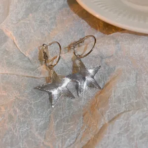 Close-up detail shot of shiny silver pentagram star hoop earrings, elegant minimalist jewelry style.